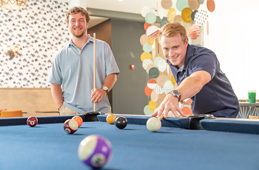 Group of young adults playing a game of pool